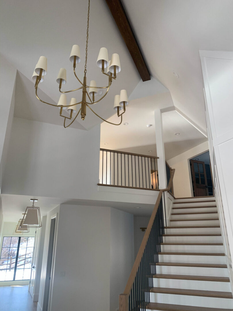 A chandelier hanging from the ceiling in front of two stairways.